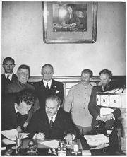 Stalin (in background to the right) looks on as Molotov signs the Molotov-Ribbentrop Pact.